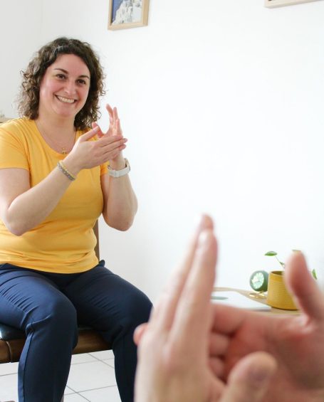 Femme souriante en t-shirt jaune forme un geste avec ses mains.